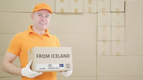 Hombre sosteniendo un paquete de cartón con texto impreso de ISLANDIA en él — Foto de Stock