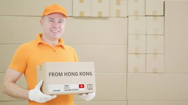 El trabajador del almacén sostiene la caja de cartón con el texto impreso de Hong Kong en ella —  Fotos de Stock