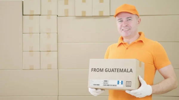 Man holding cardboard parcel with print of ROM GUATEMALA text on it — Stok Foto