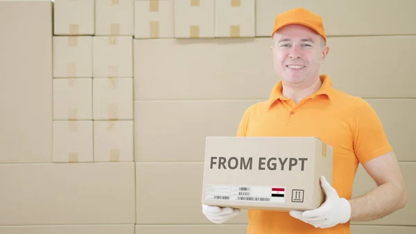 El trabajador del almacén sostiene la caja de cartón con el texto impreso de EGIPTO en ella — Foto de Stock