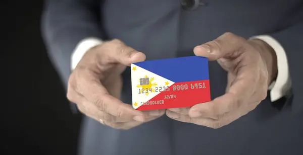 Homme d'affaires détient une carte bancaire en plastique avec drapeau imprimé des Philippines, numéros fictifs — Photo