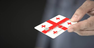 Man gives plastic bank card with printed flag of Georgia. Fictional numbers clipart