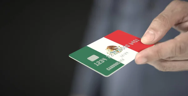 Homem dá cartão de banco de plástico com bandeira impressa do México. Números fictícios — Fotografia de Stock