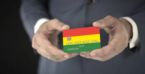 Бізнесмен тримає пластикову картку з друкованим прапором Болівії, знімальний майданчик, вигадані номери — стокове фото