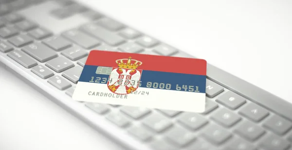 Tarjeta bancaria de plástico que representa la bandera de Serbia en el teclado de la computadora. Números de ficción — Foto de Stock