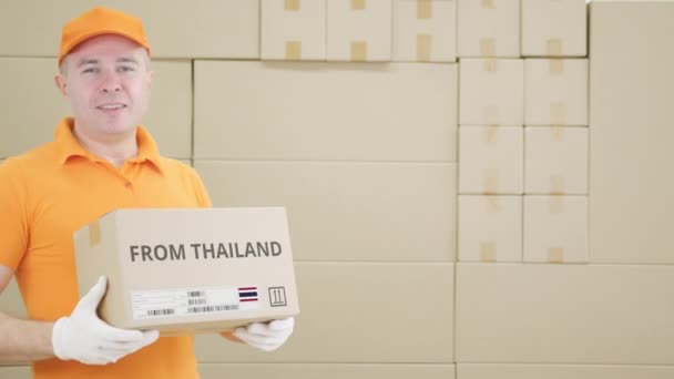 Pracownik magazynu trzyma paczkę z napisem "Z Tajlandii" — Wideo stockowe