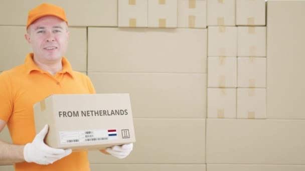 Man holding cardboard parcel with printed FROM NETHERLANDS text on it — Stock Video