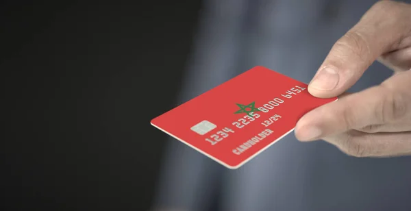 Ο άνθρωπος προσφέρει πλαστική τραπεζική κάρτα με τυπωμένη σημαία του Μαρόκου. Φανταστικοί αριθμοί — Φωτογραφία Αρχείου