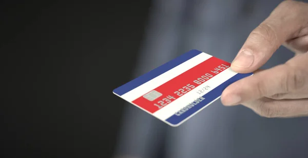 Man geeft plastic bankkaart met gedrukte vlag van Costa Rica. Fictieve nummers — Stockfoto