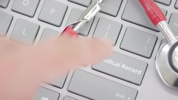 Tangan mendorong kunci RECORD MEDIKAL pada papan ketik dekat stetoskop — Stok Video
