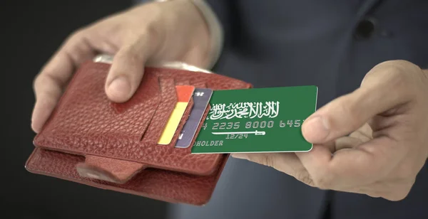 Vytahování kreditní karty s vlajkou Saúdské Arábie z peněženky, fiktivní číslo karty — Stock fotografie