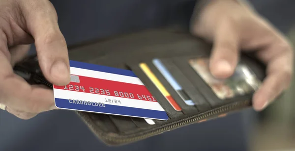 코스타리카 국기가 달린 플라스틱 은행 카드를 지갑에서 꺼내는 가상의 카드 번호 — 스톡 사진