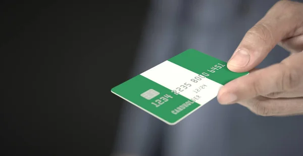 Homem dá cartão de banco de plástico com bandeira impressa da Nigéria. Números fictícios — Fotografia de Stock