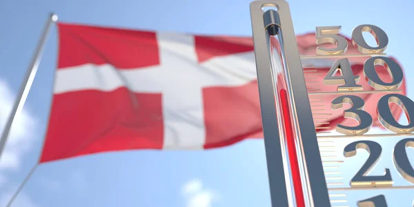 温度計は、デンマークのぼやけた旗に対して高い気温を示しています。暑い天気予報関連の3Dレンダリング — ストック写真