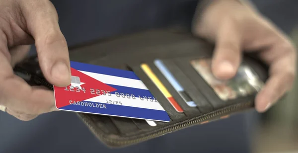 Homem puxa cartão de banco de plástico com bandeira de Cuba fora de sua carteira, número de cartão fictício — Fotografia de Stock