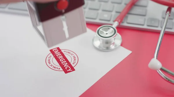 Timbre d'URGENCE DE SANTÉ PUBLIQUE sur le papier, lieu de travail des médecins — Photo