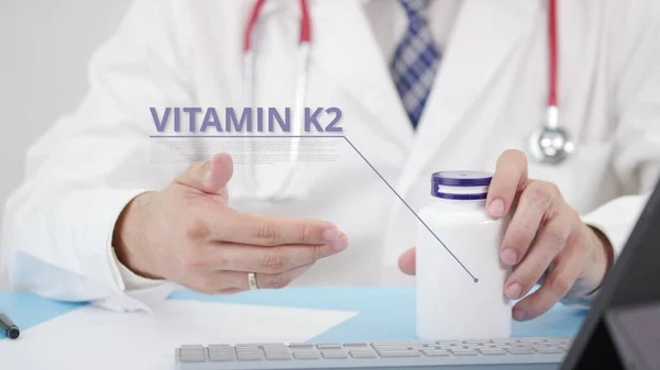 Lekarz mówi o ogólnym VITAMIN K2 w swoim miejscu pracy — Zdjęcie stockowe