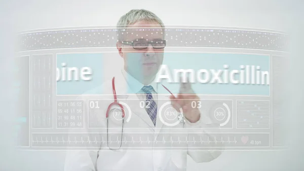 의사가 터치 스크린 표시에 AMOXICILLIN 일반 마약 이름으로 두루마리를 옮긴다 — 스톡 사진