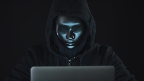 黒い服やマスクを着た未知のハッカーやロボットがコンピュータを使用しています。犯罪のボットネットやハッキングの概念的なショット — ストック動画