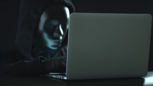 Okänd man med svart mask stjäl information från en bärbar dator. Hacka eller darknet begrepp — Stockvideo