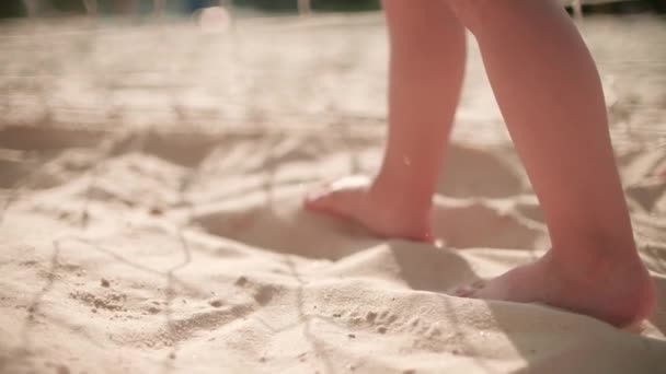 Zeitlupenaufnahme eines barfüßigen Babys, das an einem sonnigen Sommertag auf dem Sand läuft — Stockvideo