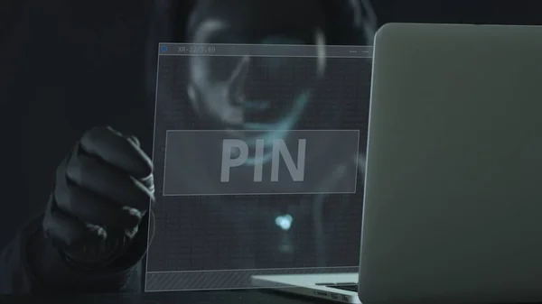 L'hacker che indossa una maschera nera estrae la linguetta PIN da un computer portatile. Il concetto di hacking — Foto Stock