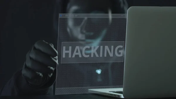 Hacker usando máscara preta puxa HACKING guia de um laptop — Fotografia de Stock