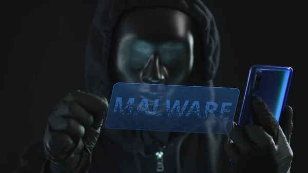 Hacker met zwart masker trekt MALWARE tab van een smartphone. Hacken concept — Stockfoto