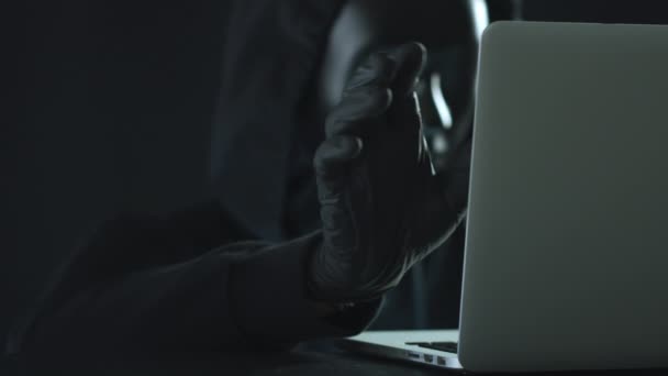 Hacker indossando maschera nera tira scheda ACCESSO da un computer portatile — Video Stock