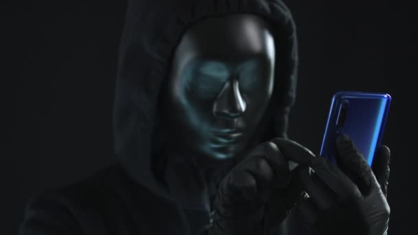 Hacker con máscara negra saca la pestaña CONTRASEÑA de un teléfono inteligente. Concepto de hackeo — Vídeo de stock