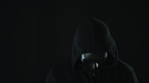Анонимный бунтарь в черной маске и капюшоне перед светящимися огнями. Концепции протеста или секретности — стоковое видео