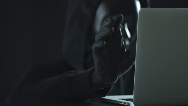 Hacker con máscara negra extrae la pestaña DATA de una computadora portátil — Vídeos de Stock