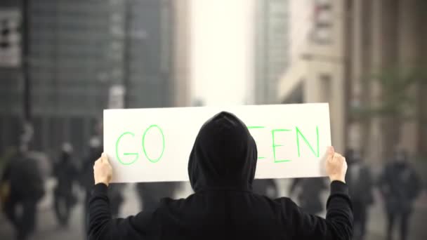 Protester v černém drží plakát s textem GO GREEN — Stock video