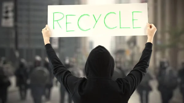 Протестующий в черном держит плакат с текстом RECYCLE — стоковое фото