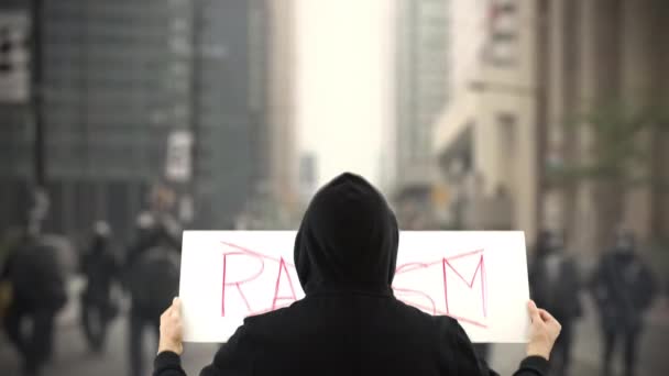 Siyah giyen protestocu üzerinde RACISM olmayan bir pankart tutuyor — Stok video