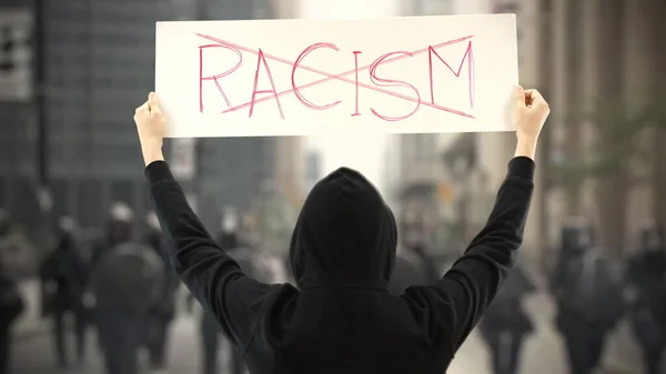 Demonstrant in het zwart draagt een bordje met GEEN RACISME tekst — Stockfoto