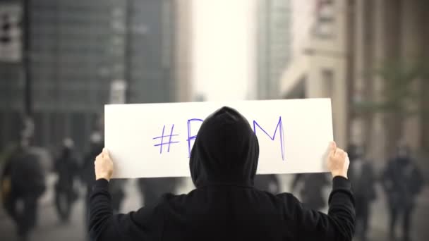 Protestante vestindo preto mantém um cartaz com BLM ou Black Lives Matter hashtag — Vídeo de Stock