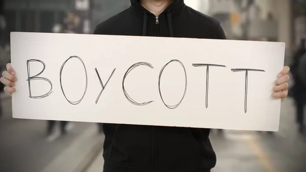 Un émeutier inconnu tient une pancarte avec du texte BOYCOTT — Photo