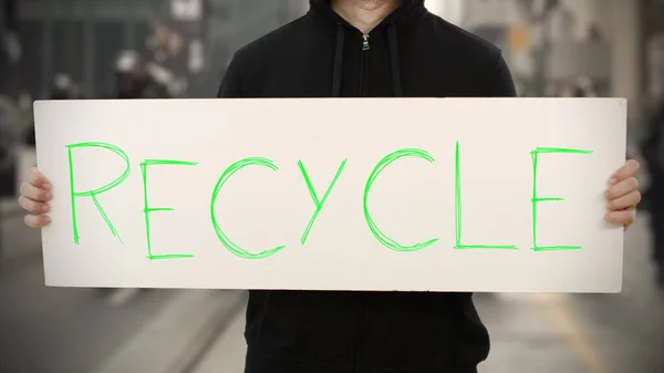 Activist in het zwart houdt een bordje met RECYCLE tekst vast — Stockfoto