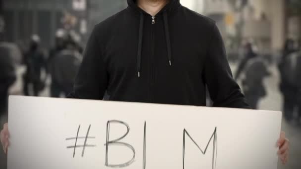 Activista vistiendo ropa oscura sostiene un cartel con BLM o etiqueta Black Lives Matter — Vídeo de stock