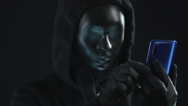 El hacker con máscara negra saca la pestaña VIRUS de un smartphone. Concepto de hackeo — Vídeo de stock