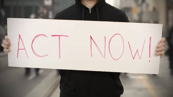 Ativista desconhecido mantém um cartaz com texto ACT NOW — Fotografia de Stock