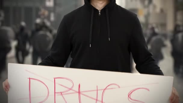 Ativista vestindo preto mantém um cartaz sem texto DRUGS — Vídeo de Stock