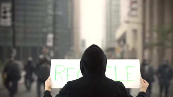 Protester wearing black holds a placard with RECYCLE text — Stock Video