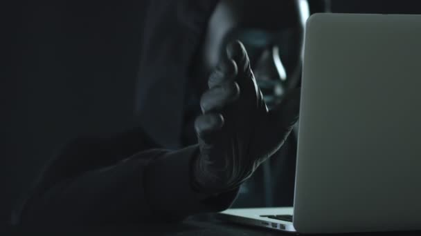 Un hacker che indossa una maschera nera estrae la linguetta CONTENUTO da un computer portatile. Il concetto di hacking — Video Stock