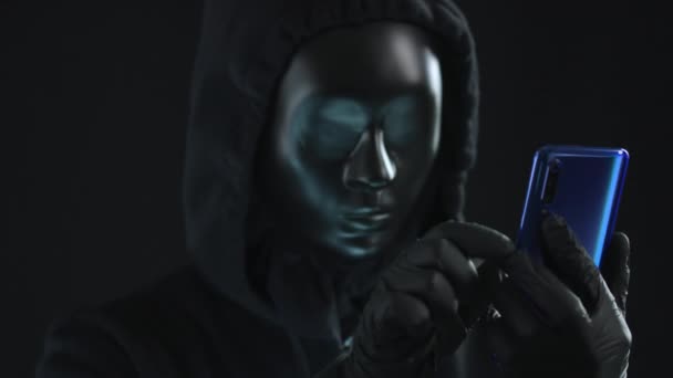 Hacker bär svart mask drar HACKING flik från en smartphone — Stockvideo