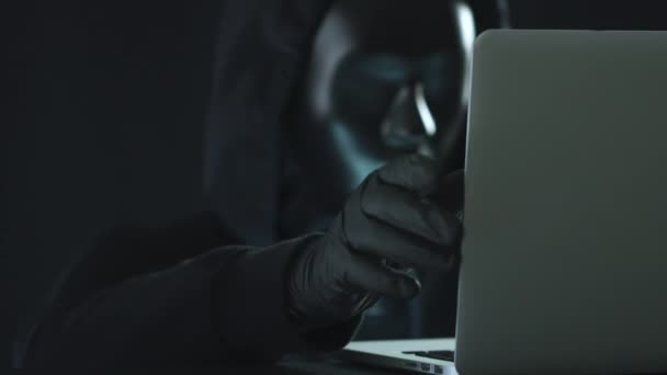 Un hacker vestido de negro saca BOTNET ficha de un ordenador portátil. Concepto de hackeo — Vídeo de stock