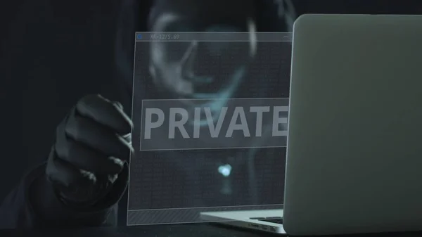 Hacker usando máscara preta puxa guia PRIVADO de um laptop. Conceito de hacking — Fotografia de Stock