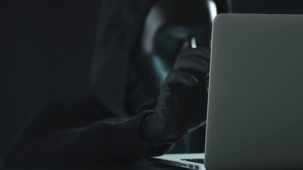 En hackare i svart drar CYBERCRIME flik från en bärbar dator. Hacka koncept — Stockvideo
