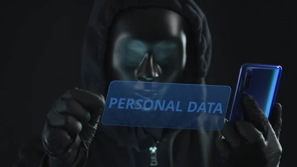 El hacker con máscara negra extrae la pestaña DATOS PERSONALES de un teléfono inteligente. Concepto de hackeo — Foto de Stock